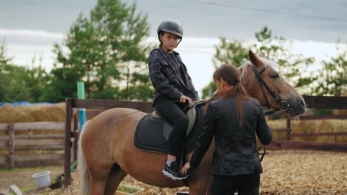 少女骑马课，女骑师正在教孩子并帮助坐在马背上