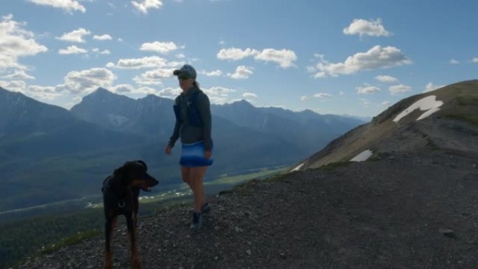 女徒步旅行者和宠物狗在山顶上享受时光
