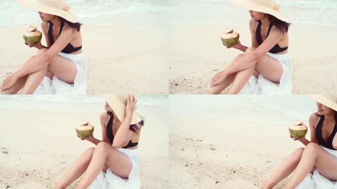 亚洲女人她在海滩上喝椰子水。