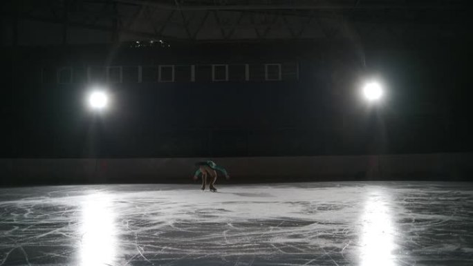 初级单身女子花样滑冰运动员正在冰场上训练，进行跳跃和骆驼旋转，在锦标赛上进行热身