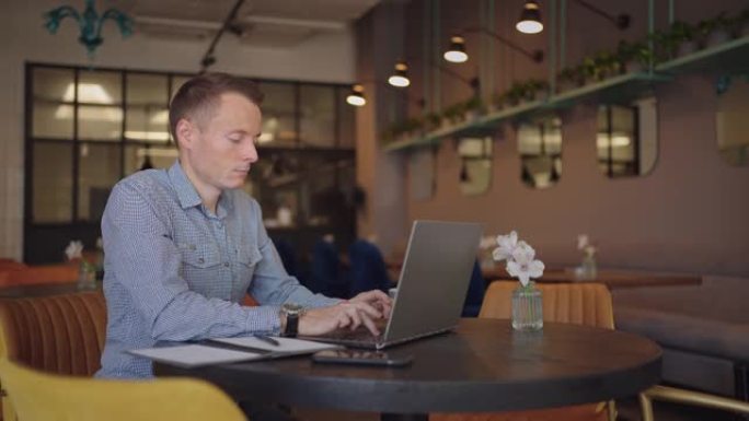 漂亮的男性开发人员或学生在咖啡馆里用笔记本电脑学习。自由职业者、远程工作、在线教育、个体户
