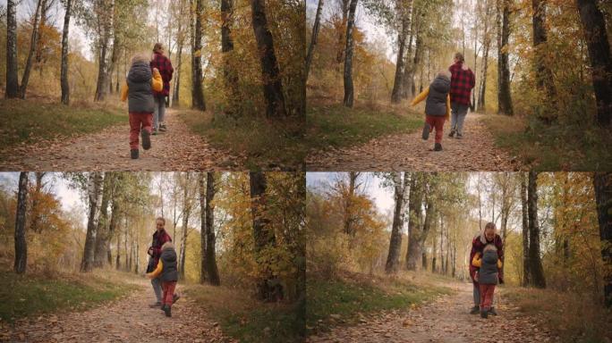 年轻的女人和小孩在秋天的森林里在人行道上奔跑，儿子跟随母亲，周末在大自然中追赶