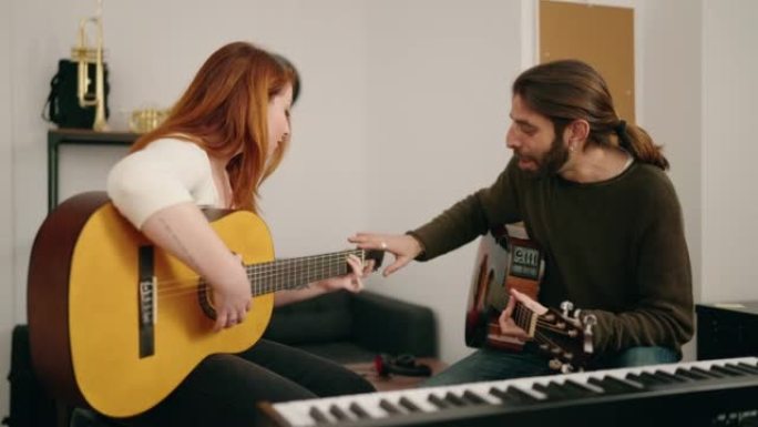 Man and woman having guitar lesson at music studio