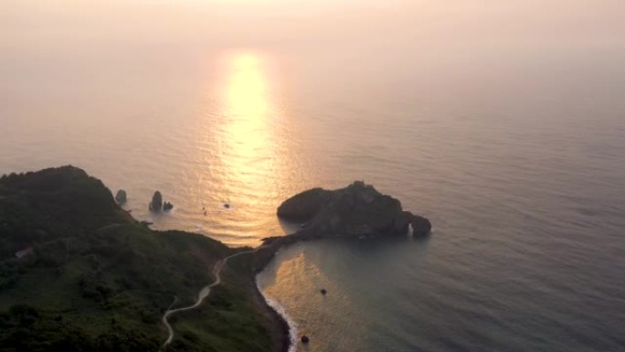 日落时的Gaztelugatxe岛。曝光不足的视频和阳光反射在比斯开高尔夫水上。