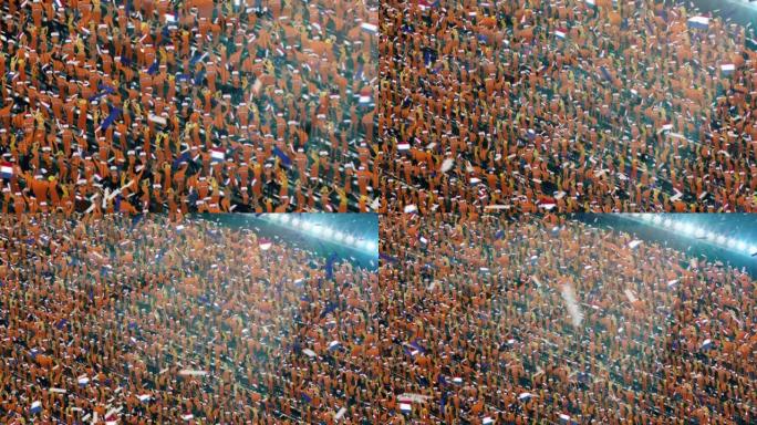 体育场看台上印有荷兰国旗颜色的人群。激动的足球迷挥舞着旗帜