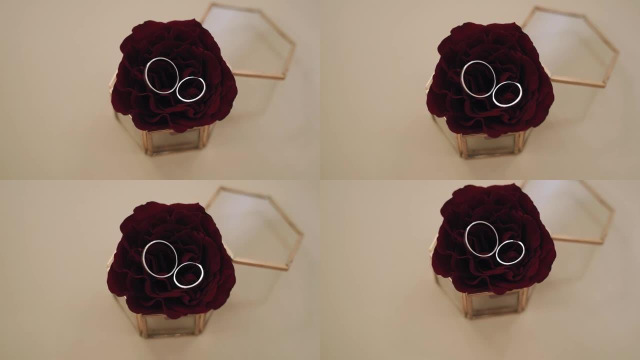 两枚戒指躺在棺材里的红玫瑰上。精美的节日物品组成