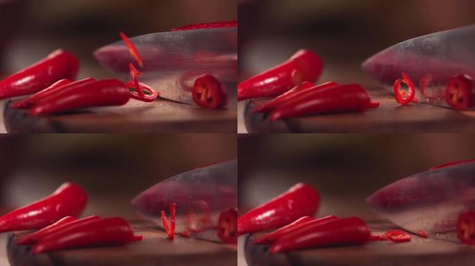 用刀在木头上慢动作切割红辣椒