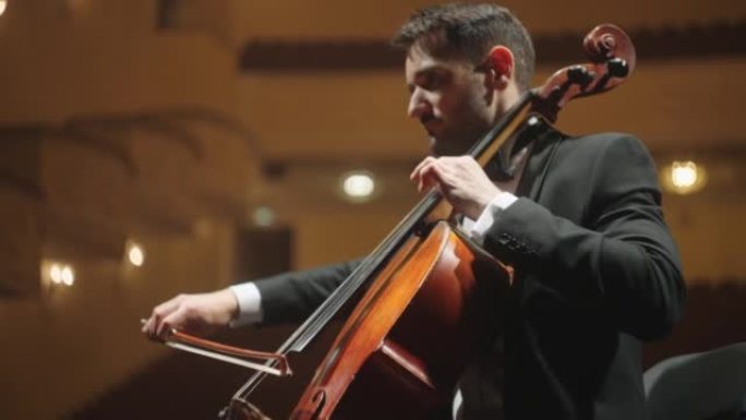 英俊的大提琴家正在歌剧院，音乐会或彩排现场演奏经典音乐