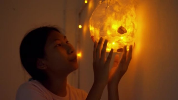 亚洲女孩在卧室玩自制圣诞灯装饰，生活方式概念。