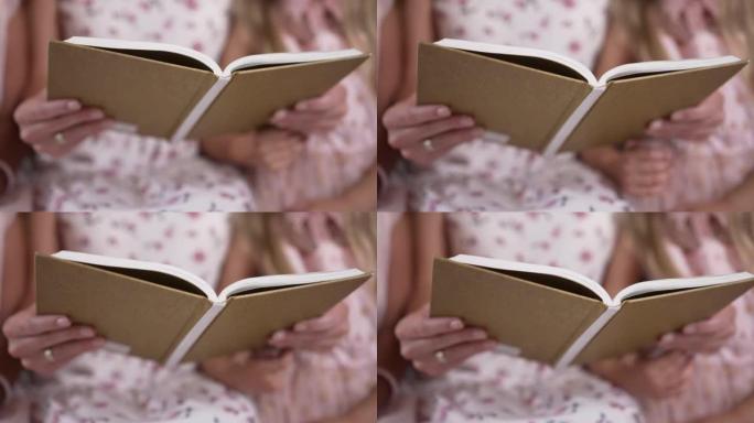 室内女性高加索人手中的特写书。无法辨认的母亲在周末晚上为女儿阅读文学。生活方式和智力概念。
