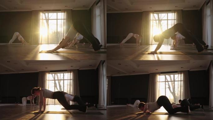 一群妇女在教练的严格指导下练习瑜伽，在日出时慢动作和阳光照射。