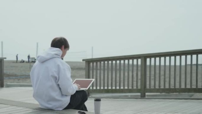 坐在海滩边的人在笔记本电脑上工作。