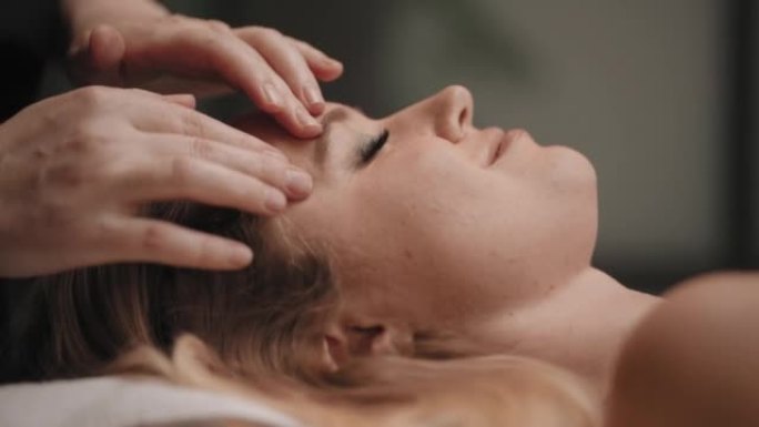 脊医正在按摩女性脸上的穴位，以放松和治疗头痛