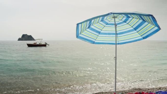 石滩上的沙滩伞，海上有渔船