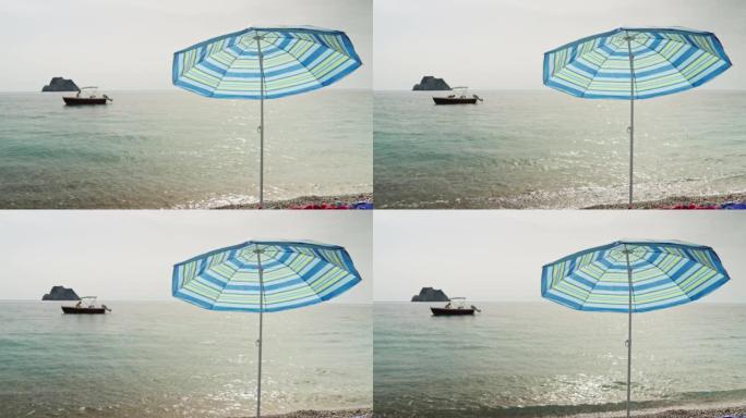 石滩上的沙滩伞，海上有渔船