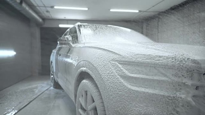 特写，洗车过程。发泡洗涤剂覆盖机器，清除污垢。慢动作，细节
