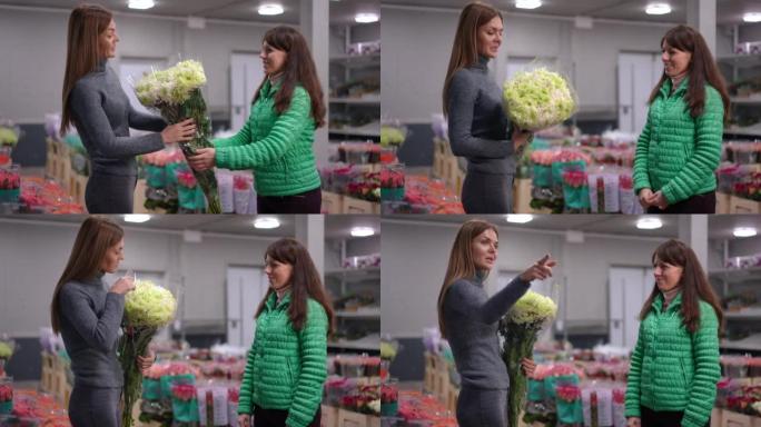 侧视图正面的白人妇女在室内的花店里传递一束鲜花。微笑着自信的花店商和顾客打手势环顾四周。