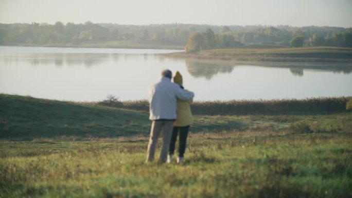 慈爱的老年夫妇在湖边拥抱