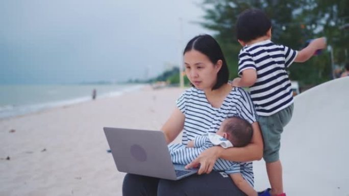 女人和她的两个儿子在泰国海滩旅行时在笔记本电脑上投资比特币。