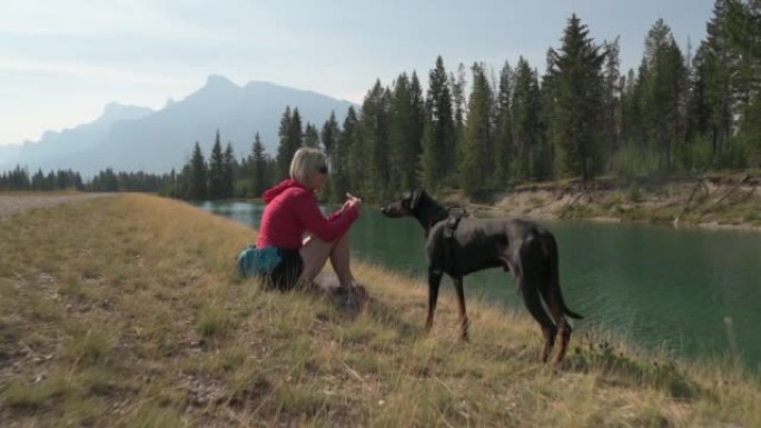 女人在山上与宠物狗一起享受户外时光