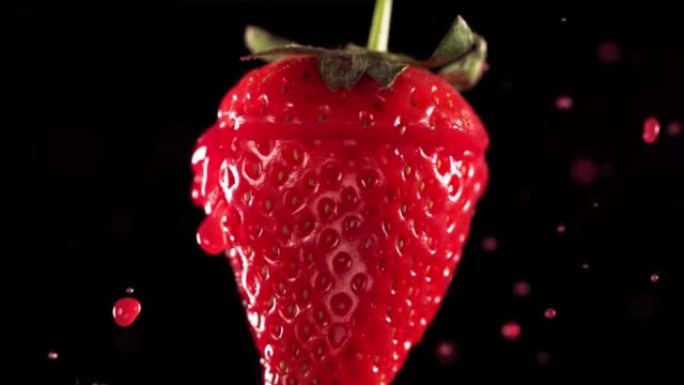 草莓切片掉落并溅到黑色背景上。食物悬浮概念。慢动作