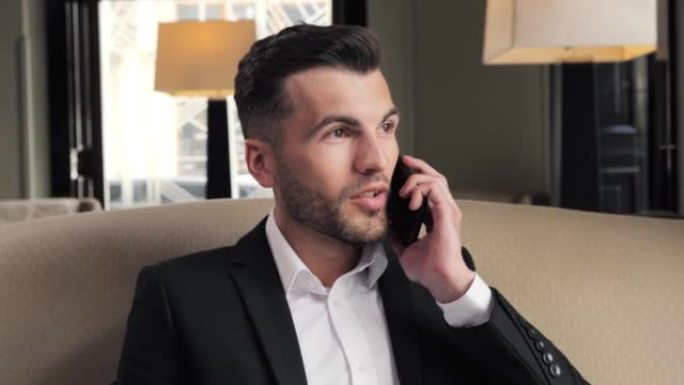 英俊时尚男人在酒店大堂打电话的肖像。在caffe的智能手机上聊天的商人。快乐的人在里面打电话。出差期