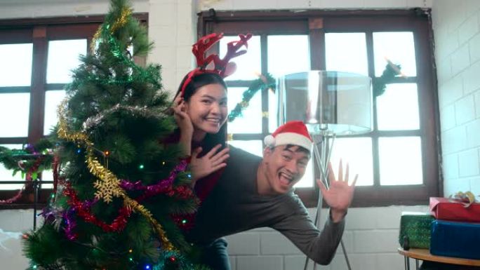 亚洲恋人互相帮助装饰白色公寓卧室的圣诞树