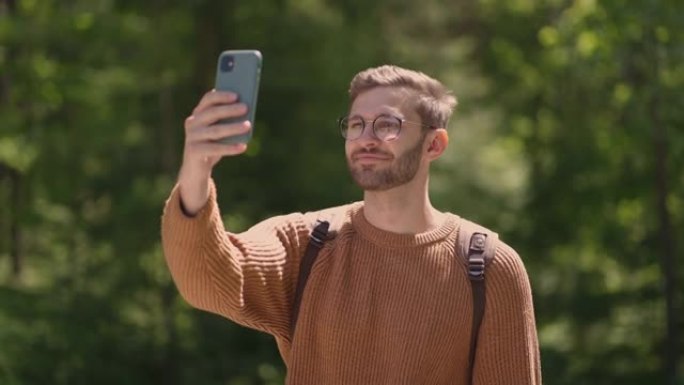 一名戴着眼镜的年轻人，留着胡须的游客在手机上拍摄了他的慢动作旅程的视频。