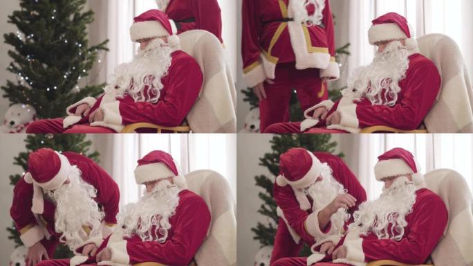 穿着红色圣诞服装的老人走进房间，年轻的圣诞老人睡在摇椅上。那家伙在除夕夜叫醒同事。