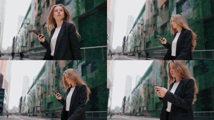 一名身穿黑色夹克的女子手里拿着手机穿过马路，在大型现代建筑的背景下环顾四周。