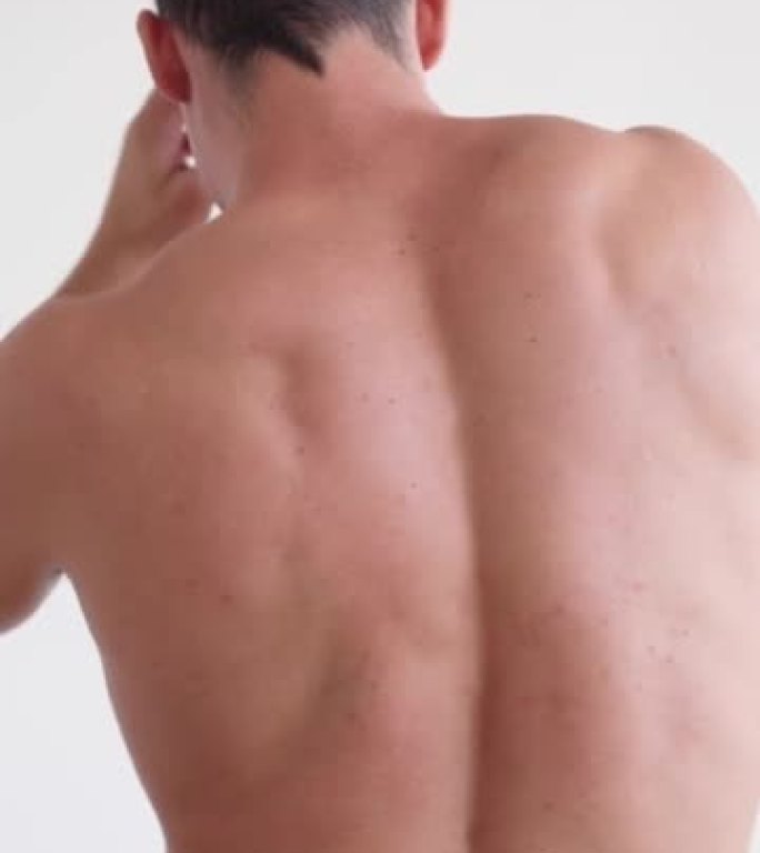 垂直视频运动员患有背痛。白底上的裸背。身体和皮肤护理的概念。颗粒男性皮肤