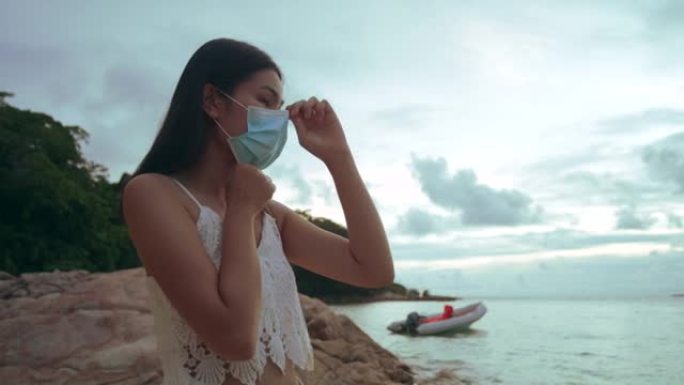 在海滩上戴着口罩的年轻女性，在病毒爆发期间旅行。