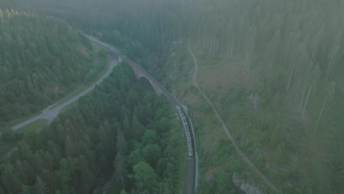 空中无人机拍摄的火车在黄昏时穿越森林