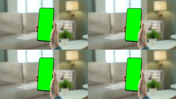 现代房间里坐在椅子上的女人的特写视图，使用带有绿色模拟屏幕色度键的电话，没有轨迹点上网观看内容视频博