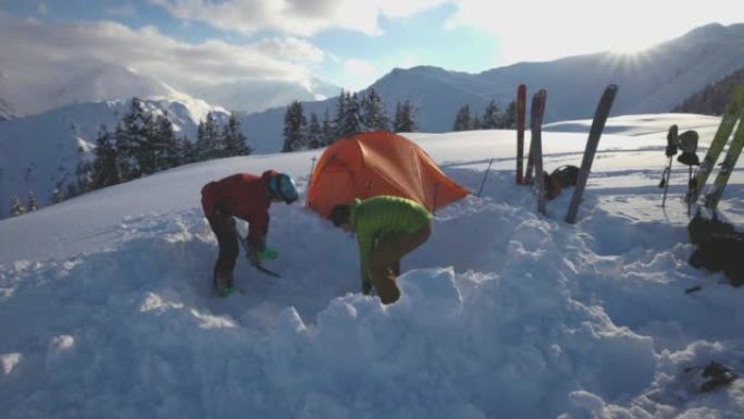 一对滑雪者在雪山上架起帐篷