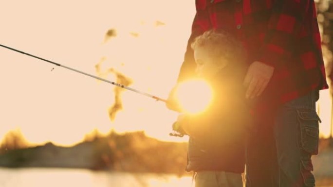 可爱的小孩在河边或湖边用鱼竿、快乐的小男孩和父亲或爷爷抓鱼