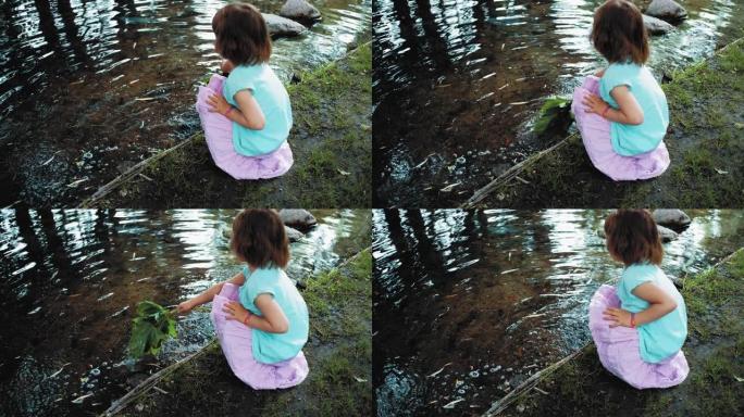 年轻的高加索女孩在无人看管的水河池塘旁玩耍，手里拿着绿树的叶子
