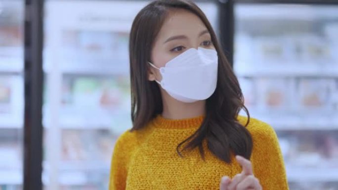 新常态新冠疫情后年轻聪明的亚洲女性在超市购物新生活方式与面罩或口罩保护手选择新鲜蔬菜水果新常态生活方