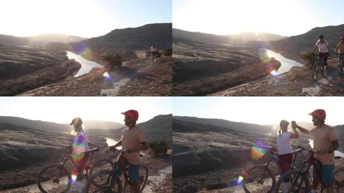 成熟的山地自行车夫妇在沙漠路径上交换击掌