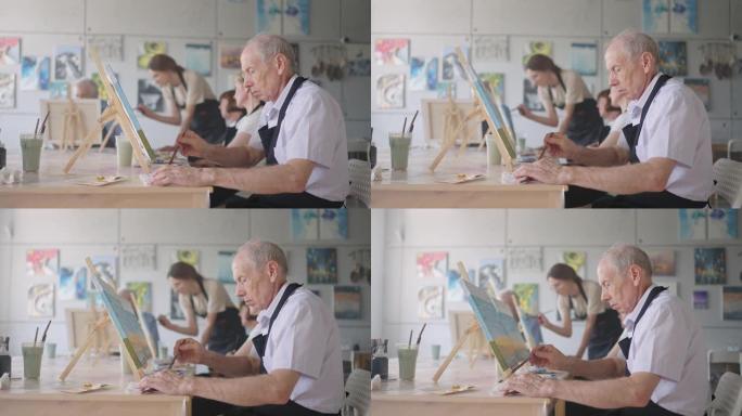 与退休的男女一起在绘画课上作为娱乐活动或疗法时微笑着快乐的老年人的侧视图