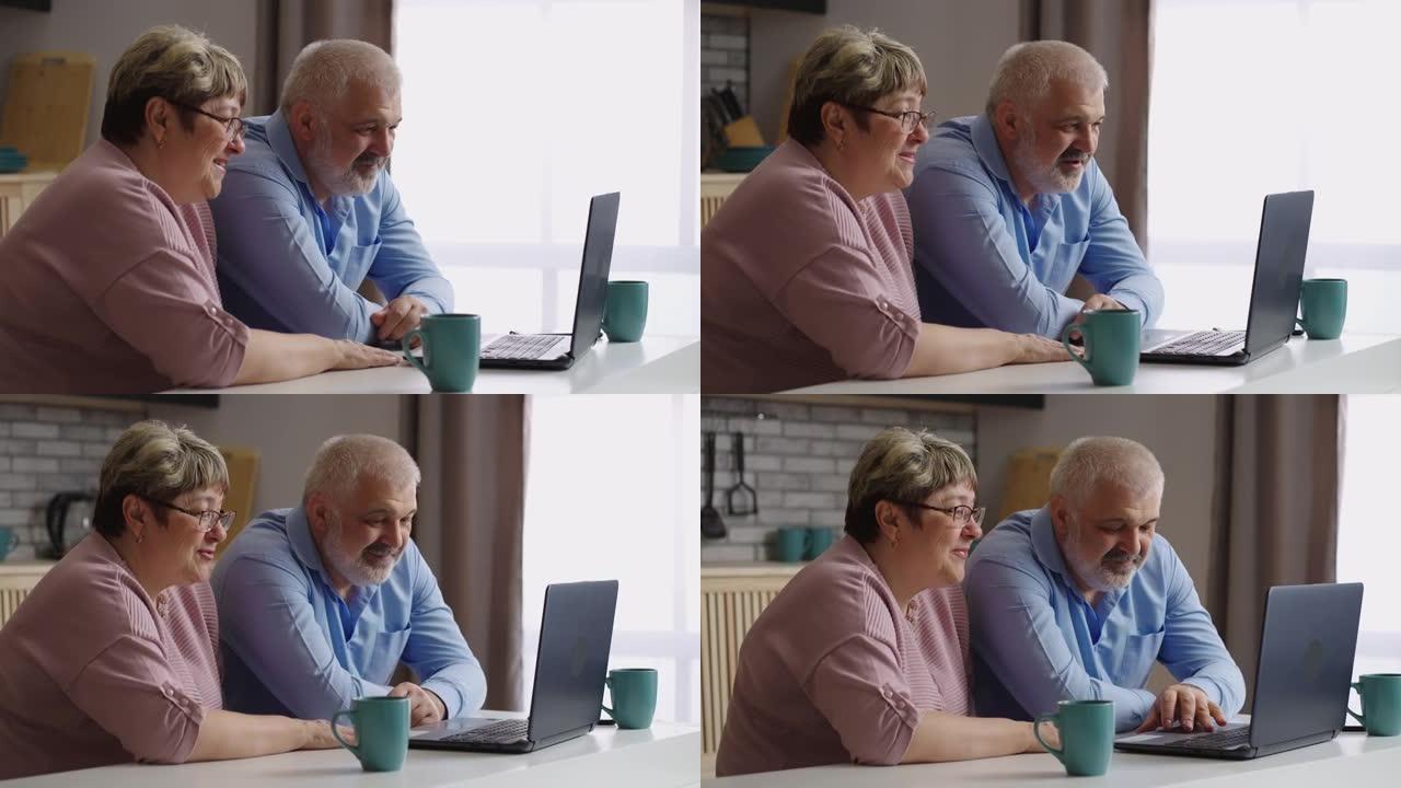 老人和女人正在通过笔记本电脑与朋友在线交流，坐在厨房，中等肖像