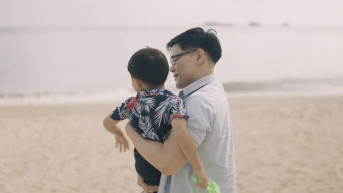 亚洲父亲带着儿子在海滩散步