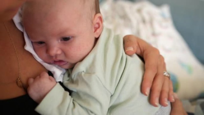 新生婴儿躺在母亲的胸前醒来，环顾四周握着她的手