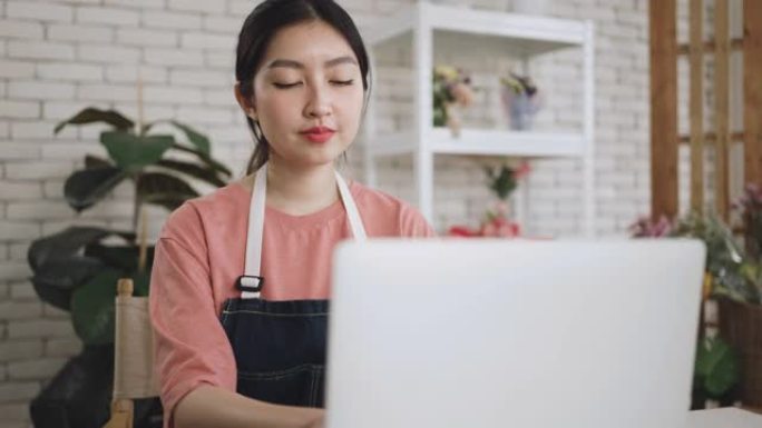 年轻的亚洲妇女正在家庭办公室的笔记本电脑上工作。