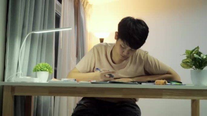 亚洲男生晚上在家做作业，生活方式理念。