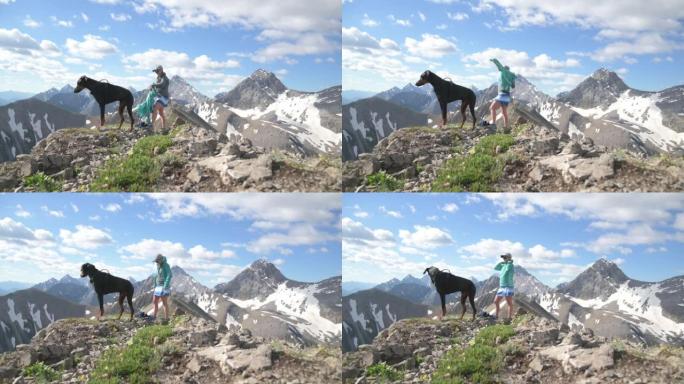 女徒步旅行者和宠物狗在山顶上享受时光