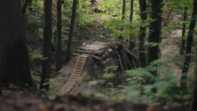 山地自行车上的森林自行车手的电影镜头加速并跳上跳板