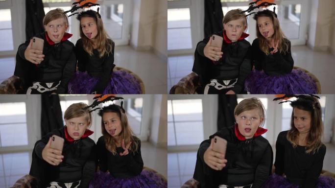 快乐的孩子们在智能手机上穿着万圣节服装自拍。两个快乐快乐的高加索儿童通过电话为社交媒体拍照。男孩和女