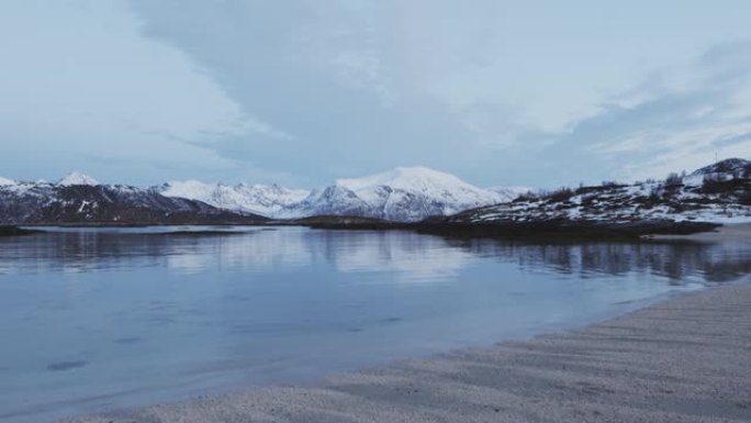 冬天特罗姆瑟海边的风景。积雪覆盖的山脉和杂草