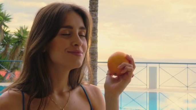 女人在露台上享受成熟的橙色水果。海景